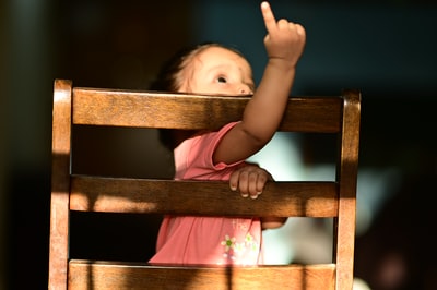 女孩在白色和粉红色的衬衫躺在棕色的木头椅子
